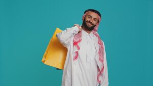 Young man holding a shopping bag outside an Islamic store filled with books and gifts.